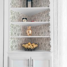 a shelf with some food on it in front of a wallpapered wall and window