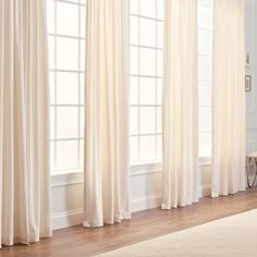 a living room with white curtains and hardwood floors