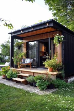 a small black shed sitting on top of a lush green field next to a wooden bench