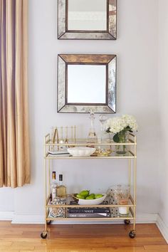 a gold bar cart with plates and bowls on it in front of a mirror above the counter