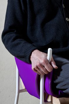 a man sitting in a chair with his hand on the seat and holding a white handle