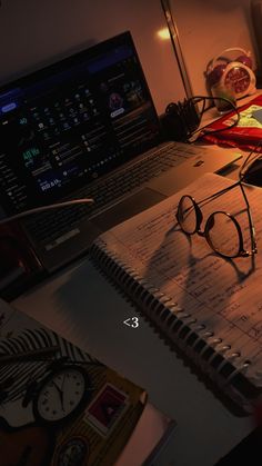 an open laptop computer sitting on top of a desk next to a pair of glasses