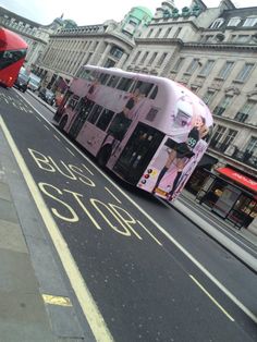 a double decker bus is driving down the street in front of some buildings and buses