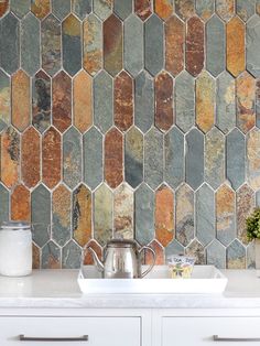 a kitchen counter with a white sink and tiled backsplash in the backround