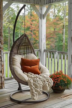 a hanging chair on a porch next to a potted plant