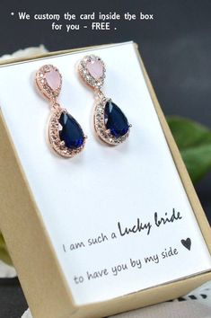 a pair of blue and pink earrings sitting in a box on top of a table