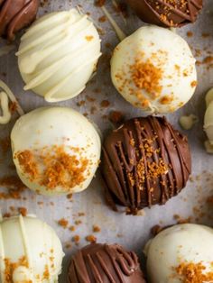 chocolates with white frosting and sprinkles are arranged on a baking sheet