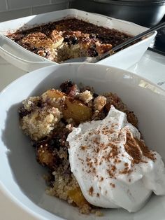 two bowls filled with food on top of a white table next to a pot full of pudding