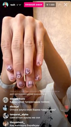 a woman's hand with pink and white nail polish on it, holding up her fingers