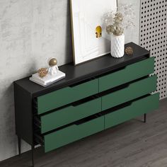 a black and green dresser sitting next to a white vase