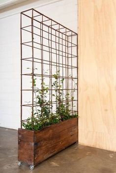 a wooden planter with plants in it next to a wall