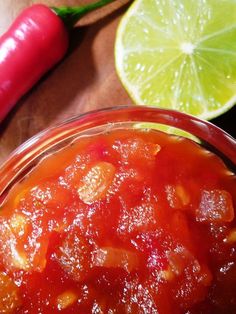 a glass bowl filled with sauce next to a sliced lime