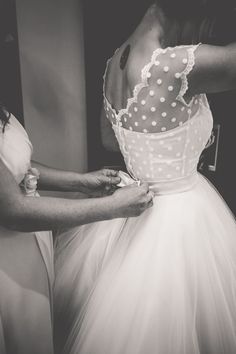 a woman in a dress getting ready to go into her wedding gown for the day