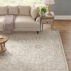 a living room with a couch, coffee table and rug on the floor in front of a window