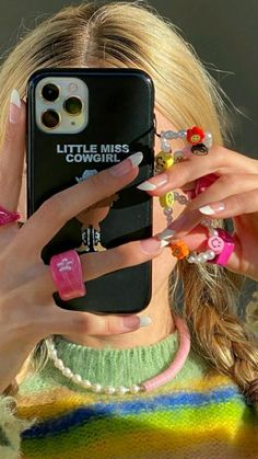 a woman holding up her cell phone to take a selfie with her nails on