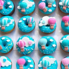 there are many cupcakes decorated with blue icing and hot air balloons on them