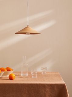 a table topped with oranges next to a bowl of water and a light fixture