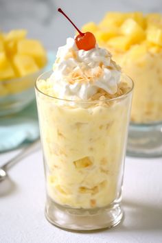 there is a dessert in the glass with whipped cream and pineapples on top