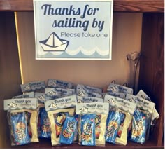 there are many bags of chips on the shelf in front of this sign that says thanks for sailing by please take one