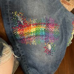 a pair of jeans with colorful sequins on the back of it and a woman's leg