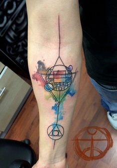 a person with a tattoo on their leg that has watercolors and geometric shapes