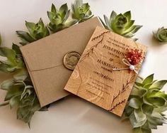 a wedding card with a wax stamp on it and succulents around it