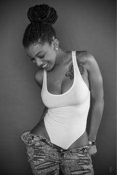 a woman in white shirt and jeans with tattoos on her chest posing for the camera