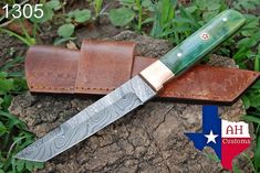 a knife sitting on top of a piece of leather next to a brown sheath with a green handle