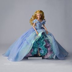 the doll is wearing a blue dress with flowers on it's skirt and has long blonde hair