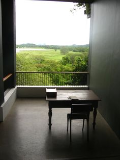 an empty room with a table and chairs on the balcony overlooking a green valley outside