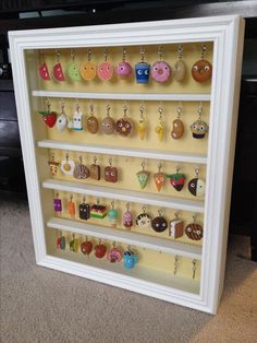 a display case with many different earrings hanging from it's sides on the floor