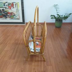 a bamboo chair with magazine rack on top of it in the middle of a wooden floor