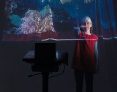 a woman standing in front of a projection screen with fish on it's wall