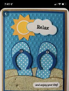 a handmade card with flip flops and the word relax on it, in front of a beach scene