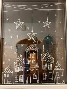 a window that has some drawings on it in front of a brick building with stars hanging from the windowsill