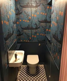 a toilet and sink in a small room with wallpapered walls on the walls