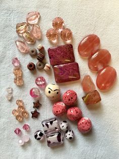 several different types of bead and glass beads on a white towel with pink accents