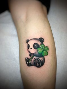 a panda bear with a clover tattoo on the arm