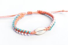 two bracelets with seashell beads and coral string on white background, closeup