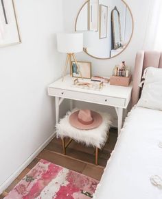 a white desk with a pink hat on top of it and a mirror in the corner