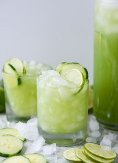 two glasses filled with cucumber and limeade next to some ice cubes