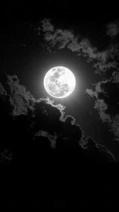 the full moon is shining brightly in the dark night sky with fluffy clouds around it