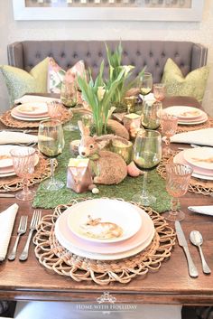 the table is set with plates, silverware and bunny figurines on it