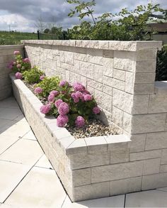 a planter filled with purple flowers sitting on top of a cement block retaining wall