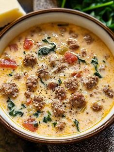 a bowl of soup with meatballs and spinach on the side next to cheese