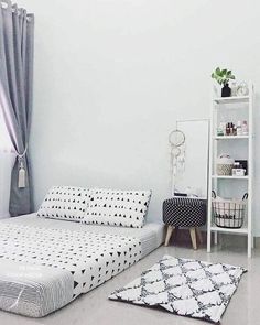 a white bed sitting next to a book shelf in a bedroom on top of a hard wood floor