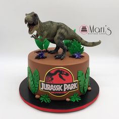 there is a cake that has a dinosaur on the top and leaves around it, as well as an image of a t - rex