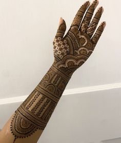 a woman's hand with henna tattoos on it, showing the intricate design