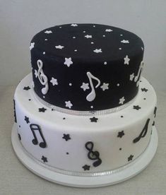 a three tiered cake decorated with musical notes and stars on the bottom, black and white