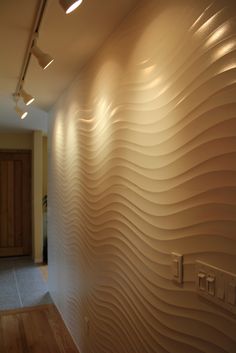 a room with a wall that has wavy waves on it and light coming from the ceiling